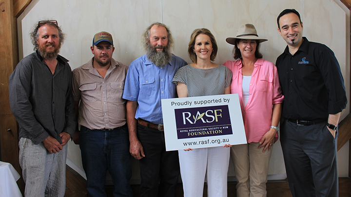 Six people standing together indoors holding a sign supporting the RASF Foundation.