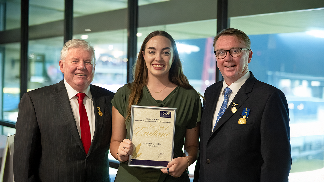 JB Fairfax Award recipient Tayla Gofton, a young brunette woman, smiling and holding a Certificate of Excellence with John Bennett and Michael Millner.