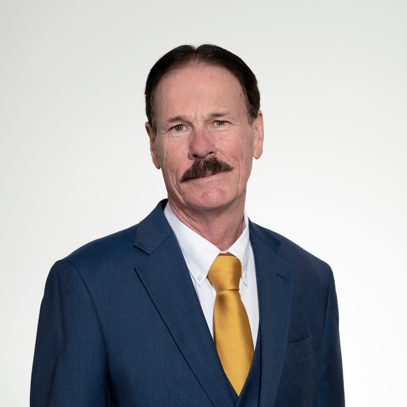 Headshot of Sheep and Wool Committee Chair John Bryson, looking ahead wearing a blue suit, white shirt, and yellow tie.