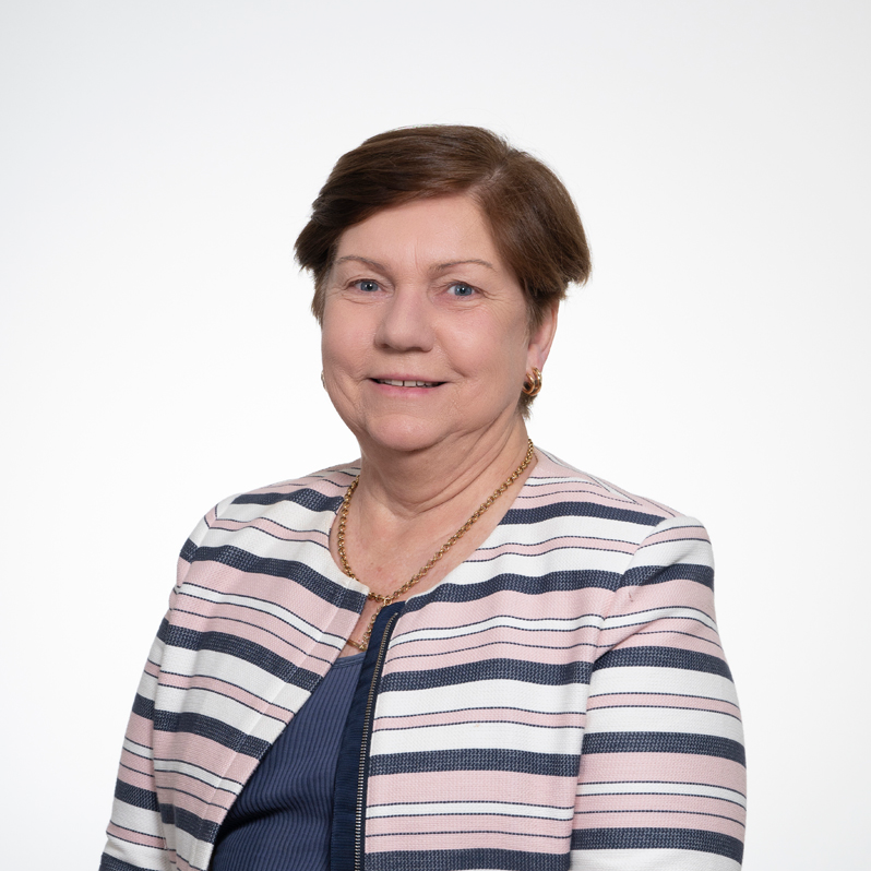Headshot of Horticulture Committee Chair Kerry Little, wearing a striped pink, white, and navy jacket over a blue top.