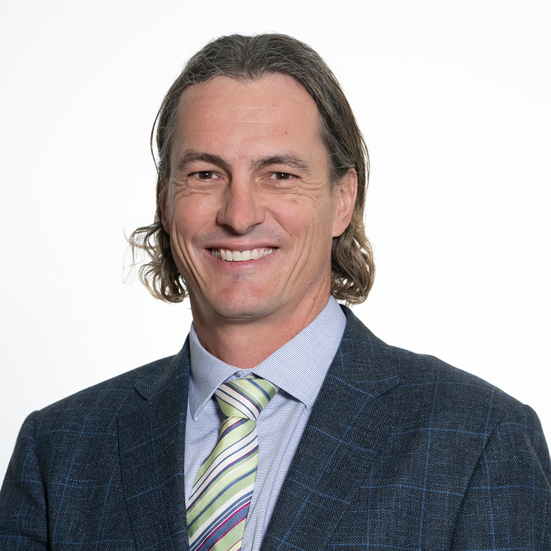Headshot of Cattle Committee Chair Michael MacCue, smiling and wearing a blue checked suit, light blue shirt, and striped tie.