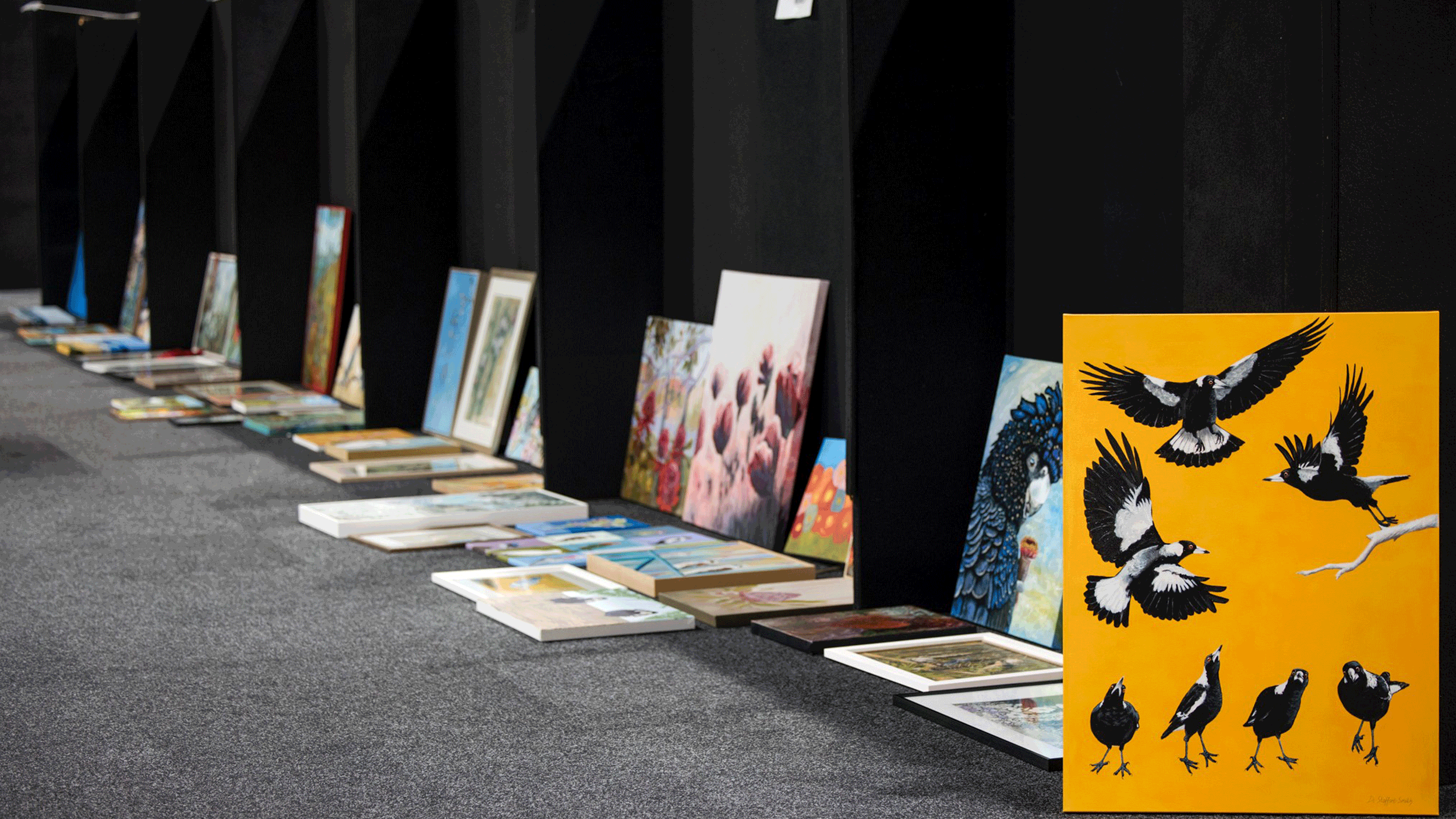 Paintings lined up for judging, including a magpie artwork, at the Sydney Royal Arts & Crafts Competition