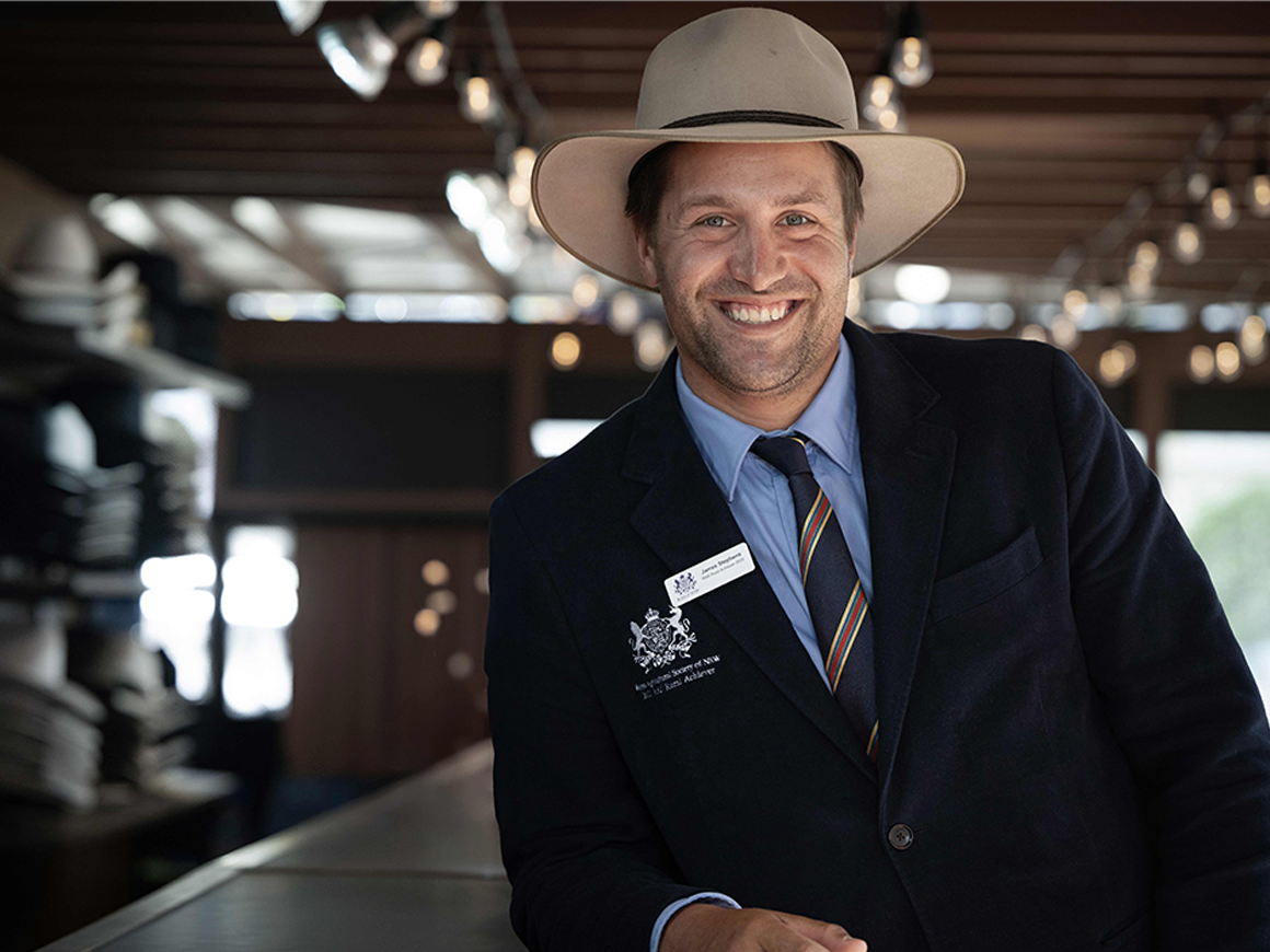 Headshot of James Stephens, a man with light brown hair and stubble, smiling in a suit and hat, winner of the 2025 RAS Rural Achiever Award.