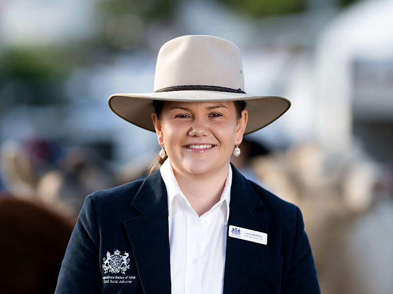 Headshot of 2026 RAS Rural Achiever winner Laura McKillop, a young woman with blonde hair tied back wearing a wide-brim hat in navy blazer.