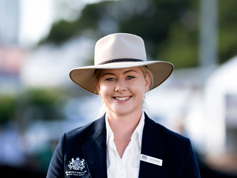 Headshot of 2026 RAS Rural Achiever finalist Loretta Nicholas, a young woman with light blonde hair tied back wearing a wide-brim hat in navy blazer.