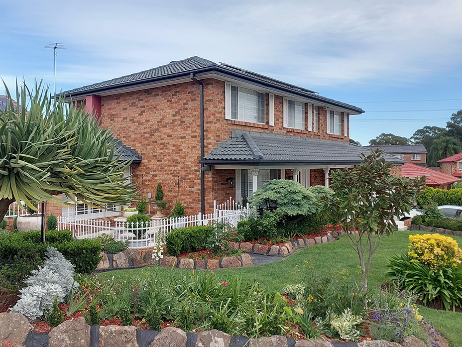 Neatly landscaped suburban garden with shaped hedges, bright spring blooms, and defined borders complementing the brick home’s façade.