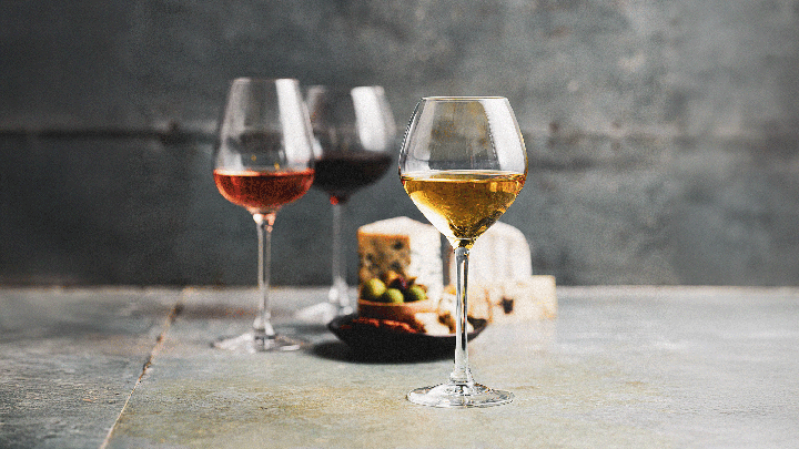 Three glasses of white, rosé, and red wine with cheese and olives in background at the Sydney Royal Wine Show.