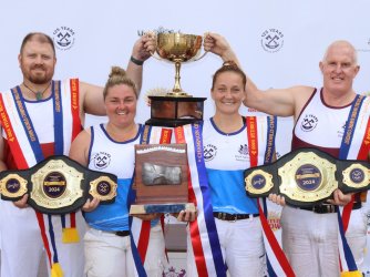Four woodchoppers celebrating with trophy and championship belts at the Sydney Royal Woodchop & Sawing Competition.