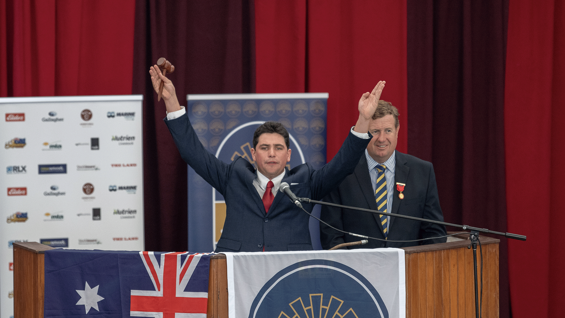 Auctioneer raising gavel on stage during the 2023 Young Auctioneers Competition.