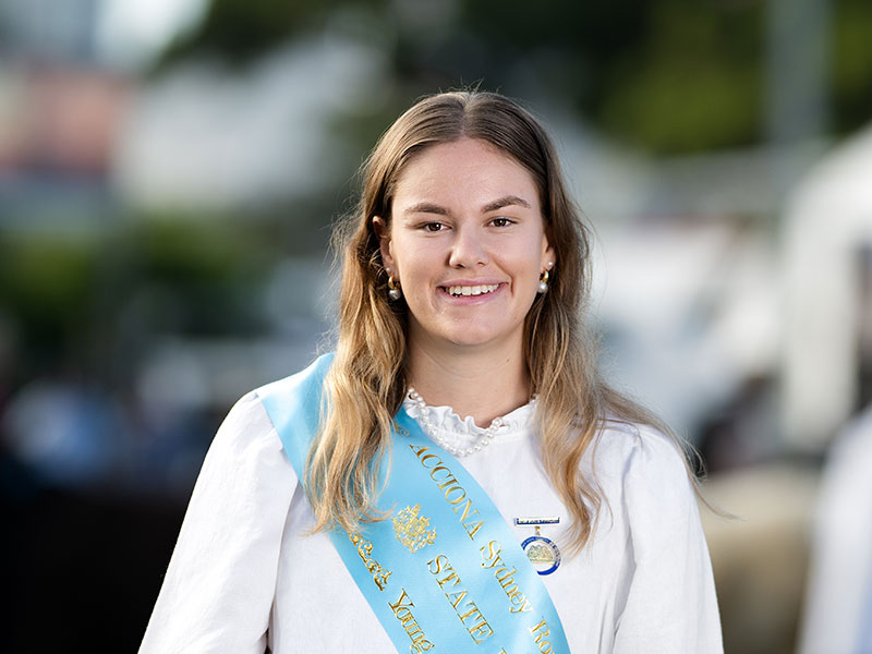 Headshot of 2026 Young Woman finalist Daneka Harry, a woman with long blonde hair, wearing a white shirt and a light blue sash.