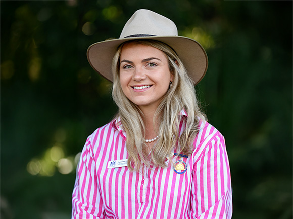 Headshot of 2025 winner Cassandra Bush, a woman with long blonde hair in a wide-brimmed hat and striped shirt.