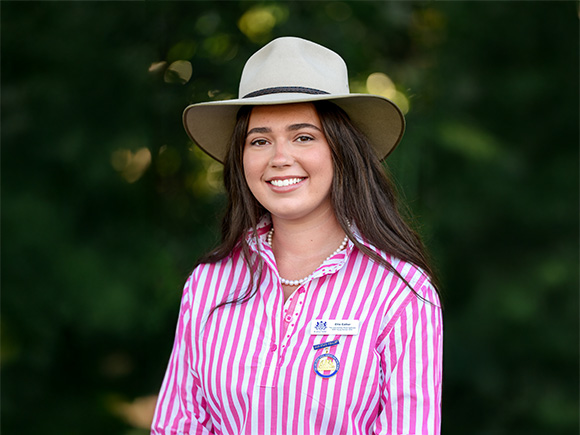 Headshot of 2025 finalist Ellie Eather, a woman with dark brown hair, hat and striped shirt, smiling.