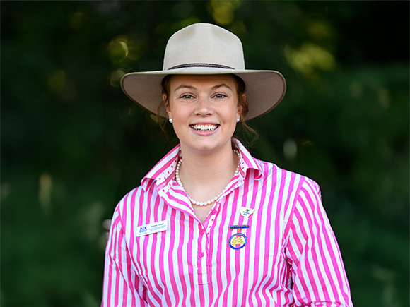Headshot of 2025 runner-up Sophie Cargill, a woman with red hair, wearing a wide-brimmed hat and striped shirt.
