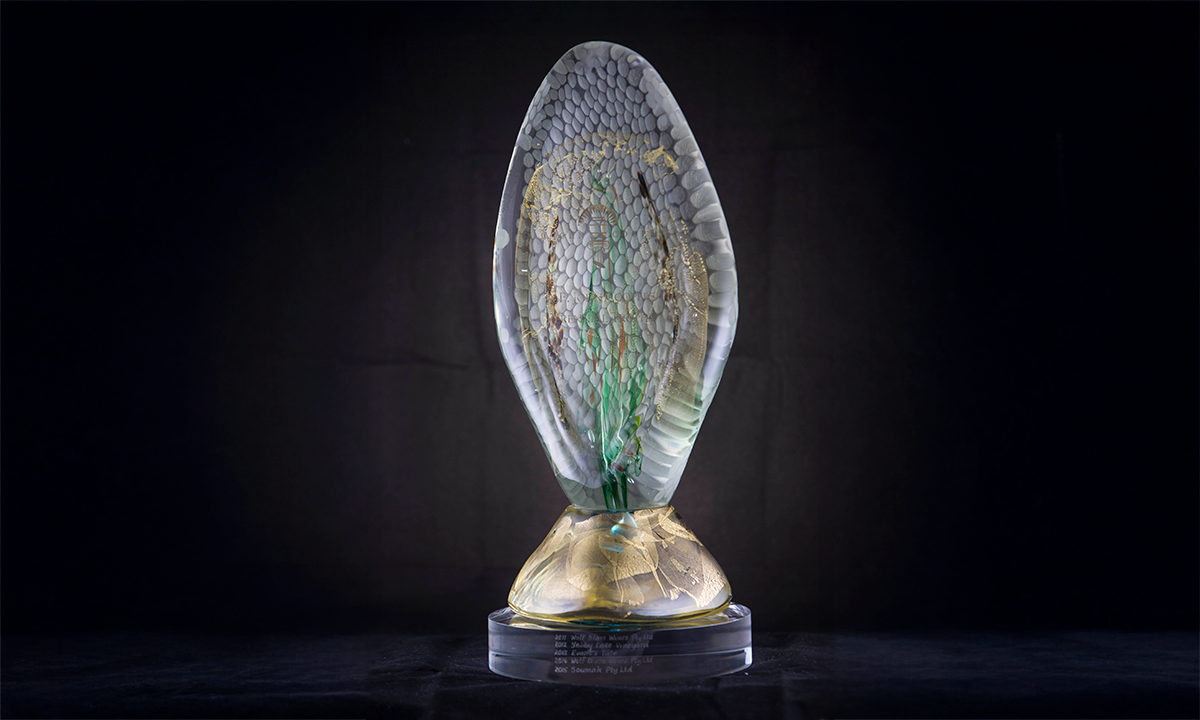 A crystal trophy that is shaped in the form of an upright leaf. Gold liquid, greens and straw are suspended throughout the clear trophy, while the bottom stand is mostly gold in colour. First presented in 2011. 