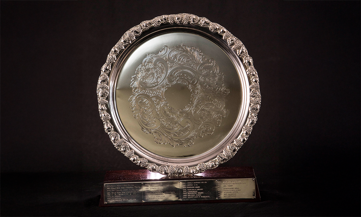 Circular plate with fruiting vine rim, place in a groove within a rectangular wooden base. First awarded in 1979.