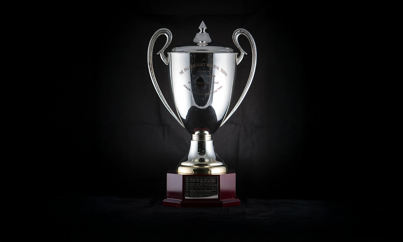 Silver twin handled urn with lid and finial, raised on an octagonal timber plinth. First presented in 1992.