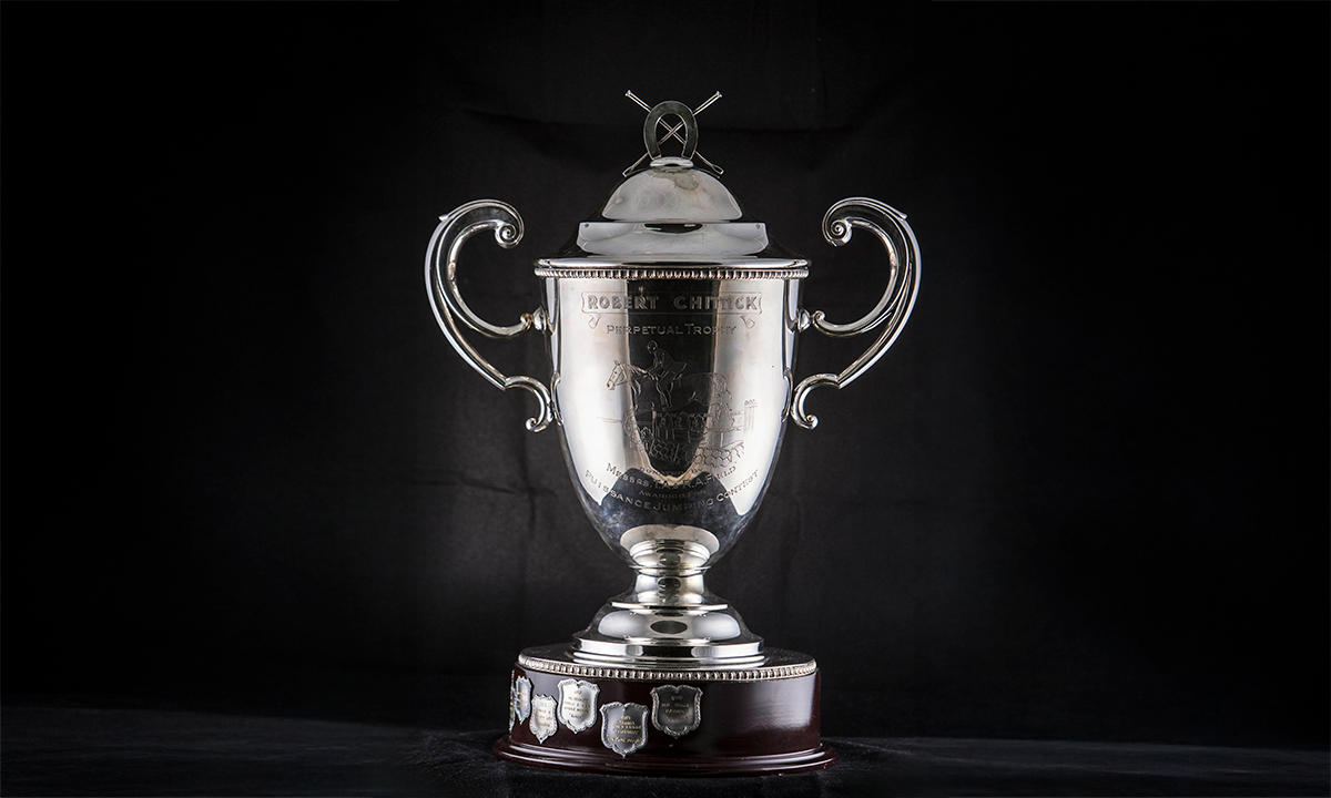 Silver-plated twin handled lidded cup engraved with a horse and rider, raised on a circular wooden base. First awarded in 1957.