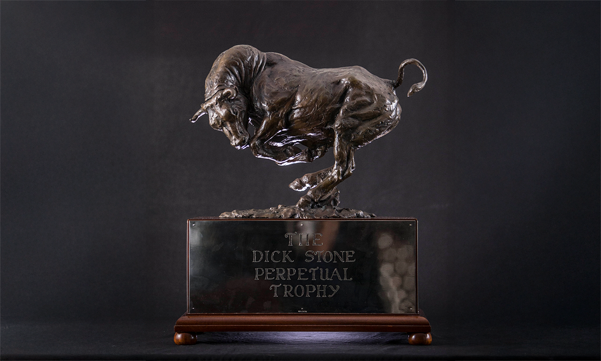 A large charging bronze bull statue mounted atop a rectangular mahogany base, with name plate attached to the front. First presented in 2012. 