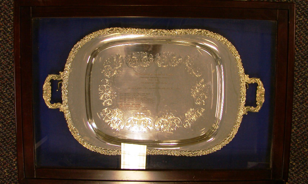 Silver tray with decorative edging and twin handles. A design is also engraved on the centre of the tray, along with names of winners. First presented in 1985.