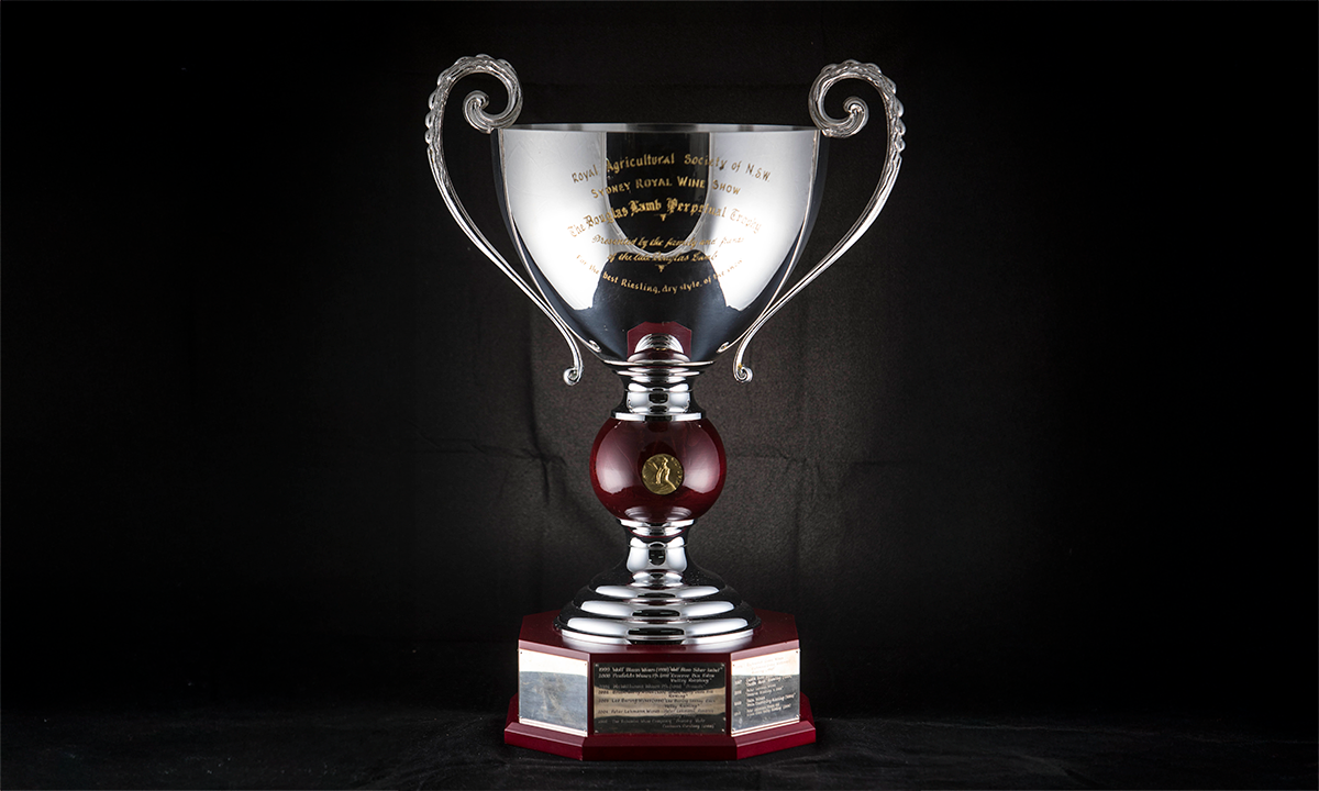 Silver trophy of twin handled cup form with foliate cast scroll handles, the stem with a rosewood knop, raised on a tiered circular stand and octagonal plinth base. First presented in 1999. 
