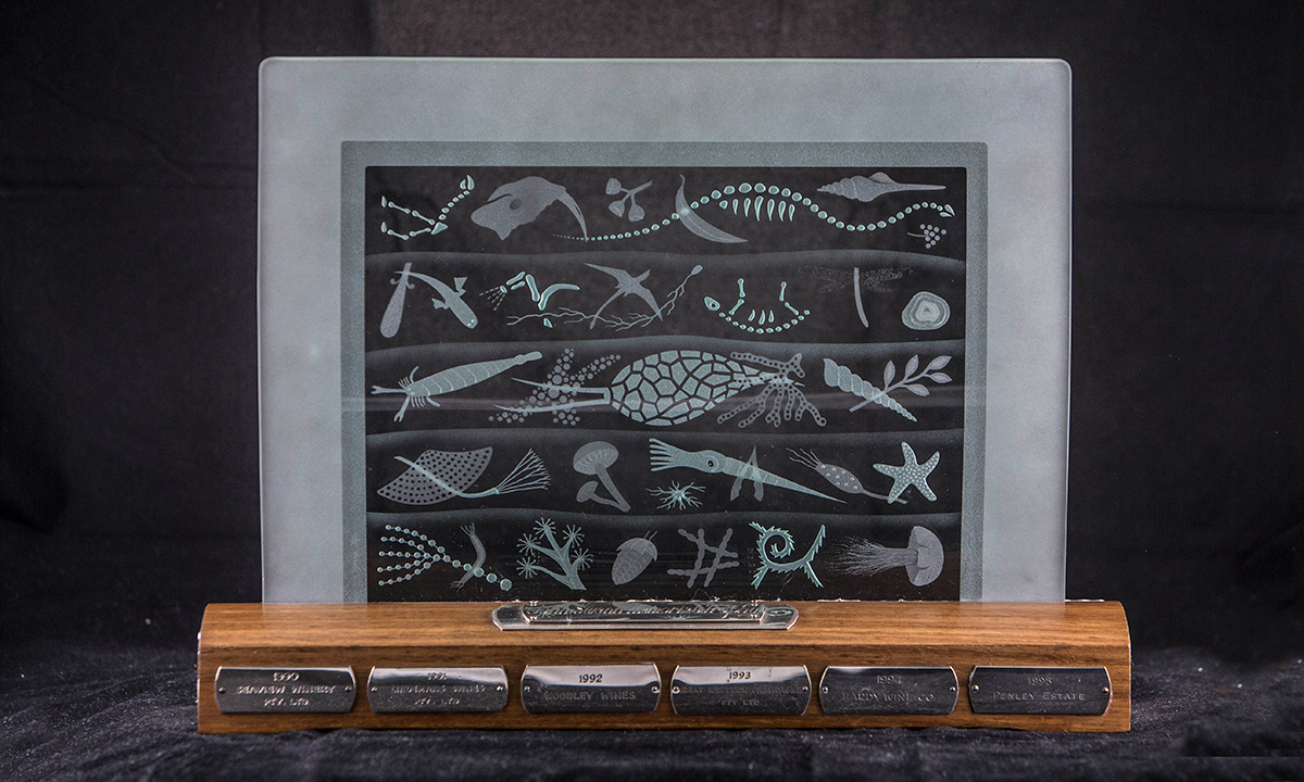 Etched satin glass on a wooden base. Images of fossils, fish, coral, and sea plants are arranged in levels denoting time periods. First awarded in 1990.