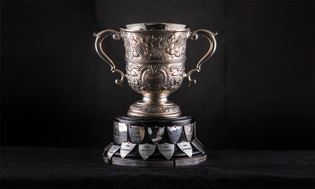 Silver twin handled loving cup with scroll handles that was later embossed with fruiting vine and C-scroll decoration. First presented in 1974.