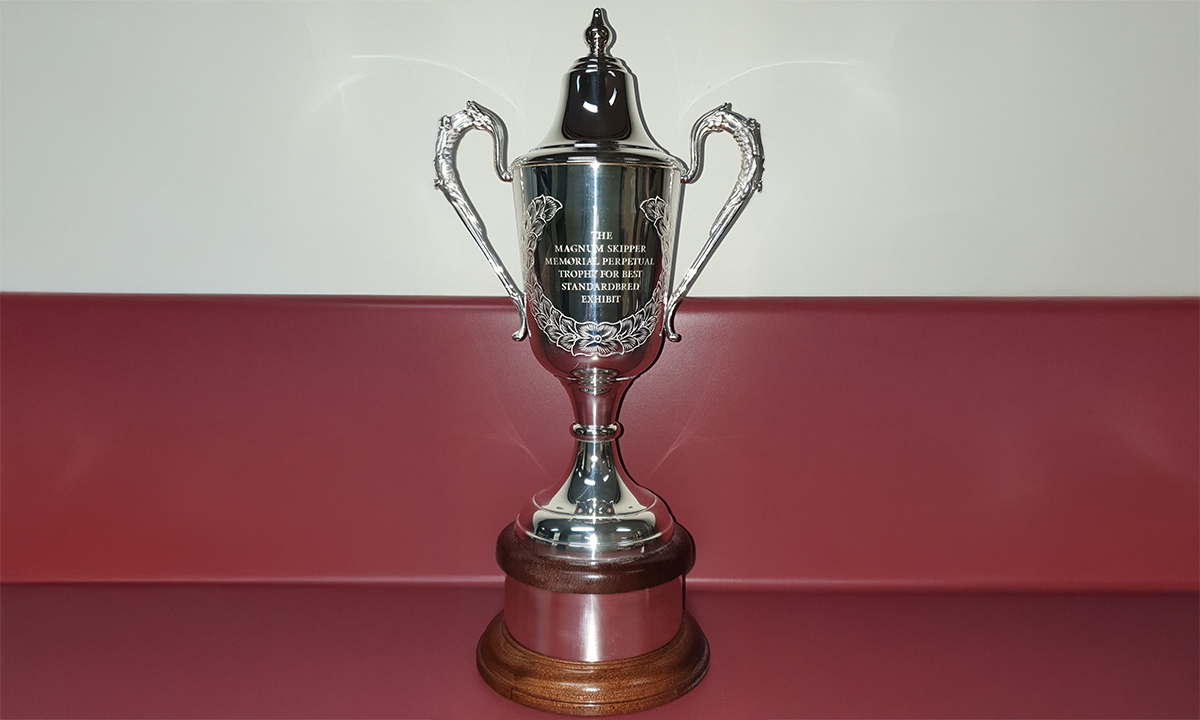 Twin-handled cup with a laurel wreath on one side, and a conical lid. Cup is mounted on a mahogany base with a silver band engraved with the names of previous winners. First awarded in 2022.