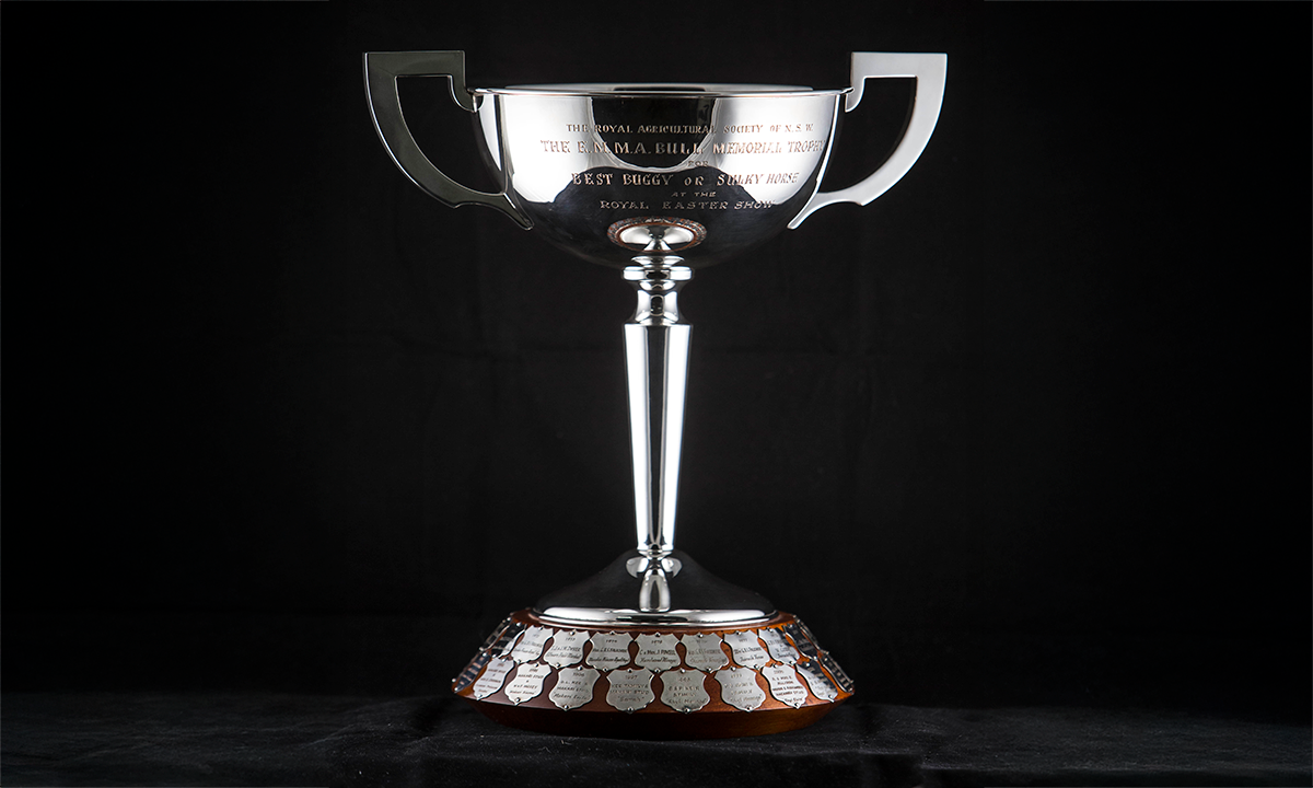 Gold coloured twin handled urn with an embossed lower body, raised on a stepped base. First presented in 1996. 