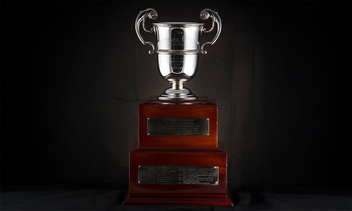 Sterling silver twin handled trophy cup with flying scroll handles. Mounted on a rosewood finished square wooden base. First awarded in 1988.