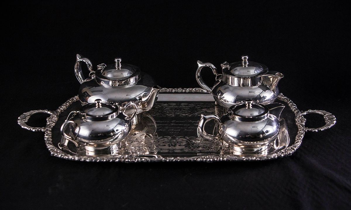 A four-piece silver tea service on a silver rectangular twin handled tray with decorative edging. First presented in 1984. 