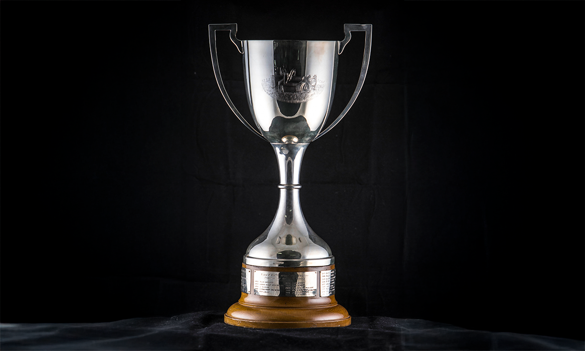 Silver twin handled cup engraved with horses pulling a plough, raised on an ash timber base. First presented in 1992. 