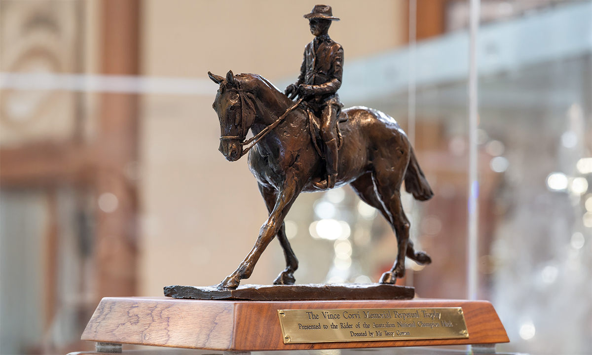 Bronze sculpture of horse and rider in motion, mounted to a wooden base. First presented in 2021.