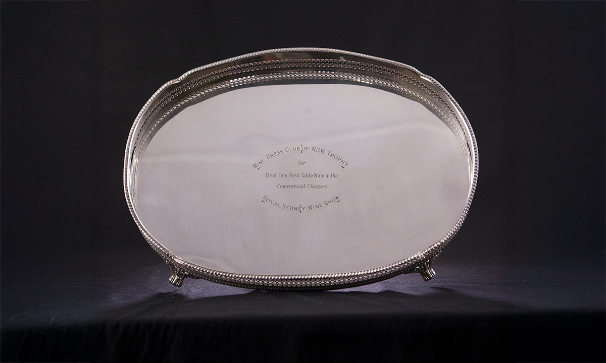 Silver oval tray with raised sides and open grip handles, raised on scroll feet. The rim is engraved on the outside with the names of the winners. First presented in 1990. 