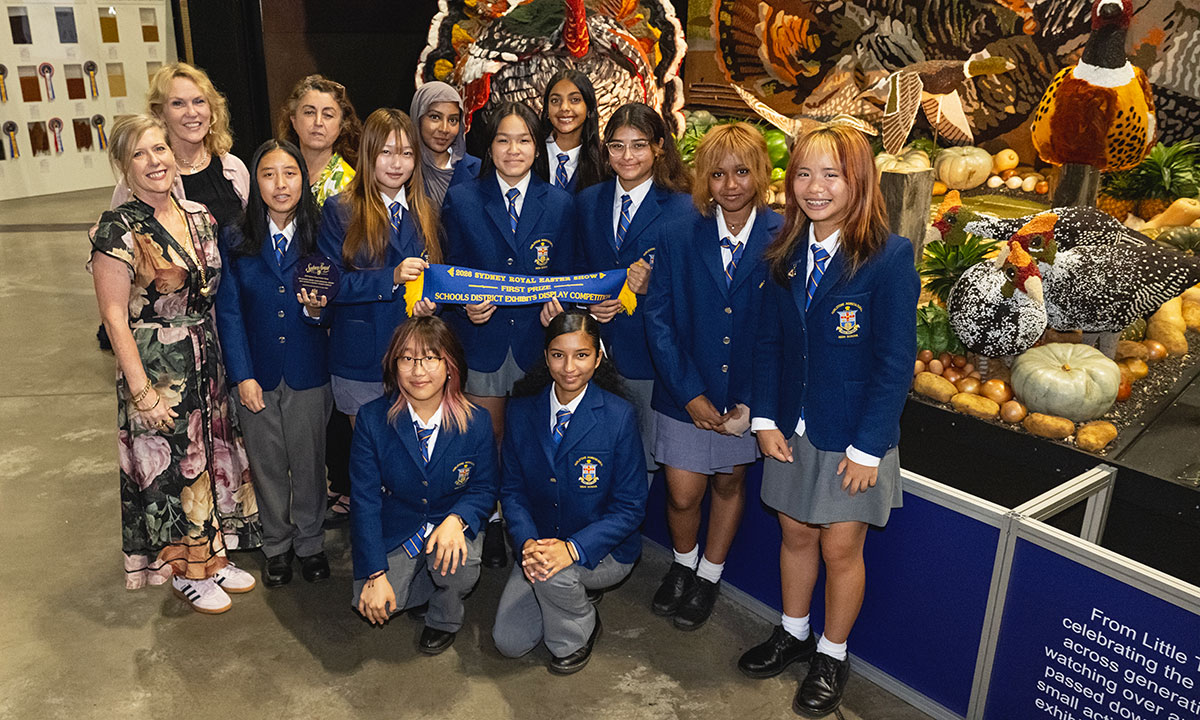 Uniformed school girls from Hurlstone Agricultural High School standing with their teachers in front of their District Exhibits display.